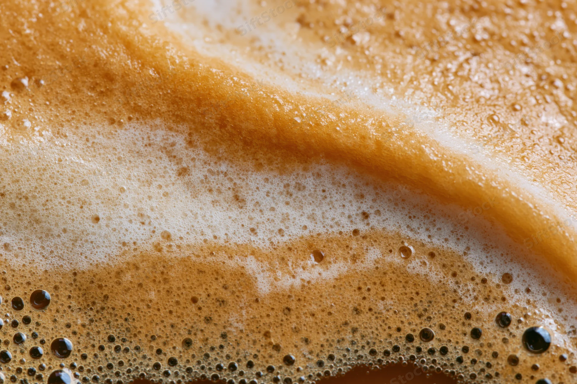 Close-up of coffee crema surface with bubbles and foam filling the frame