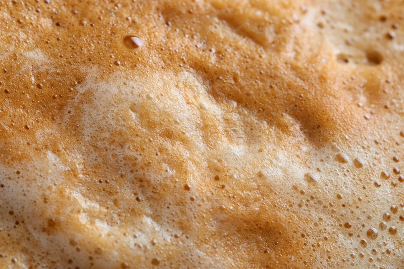 Close-up of coffee crema surface with golden foam and bubbles filling the frame