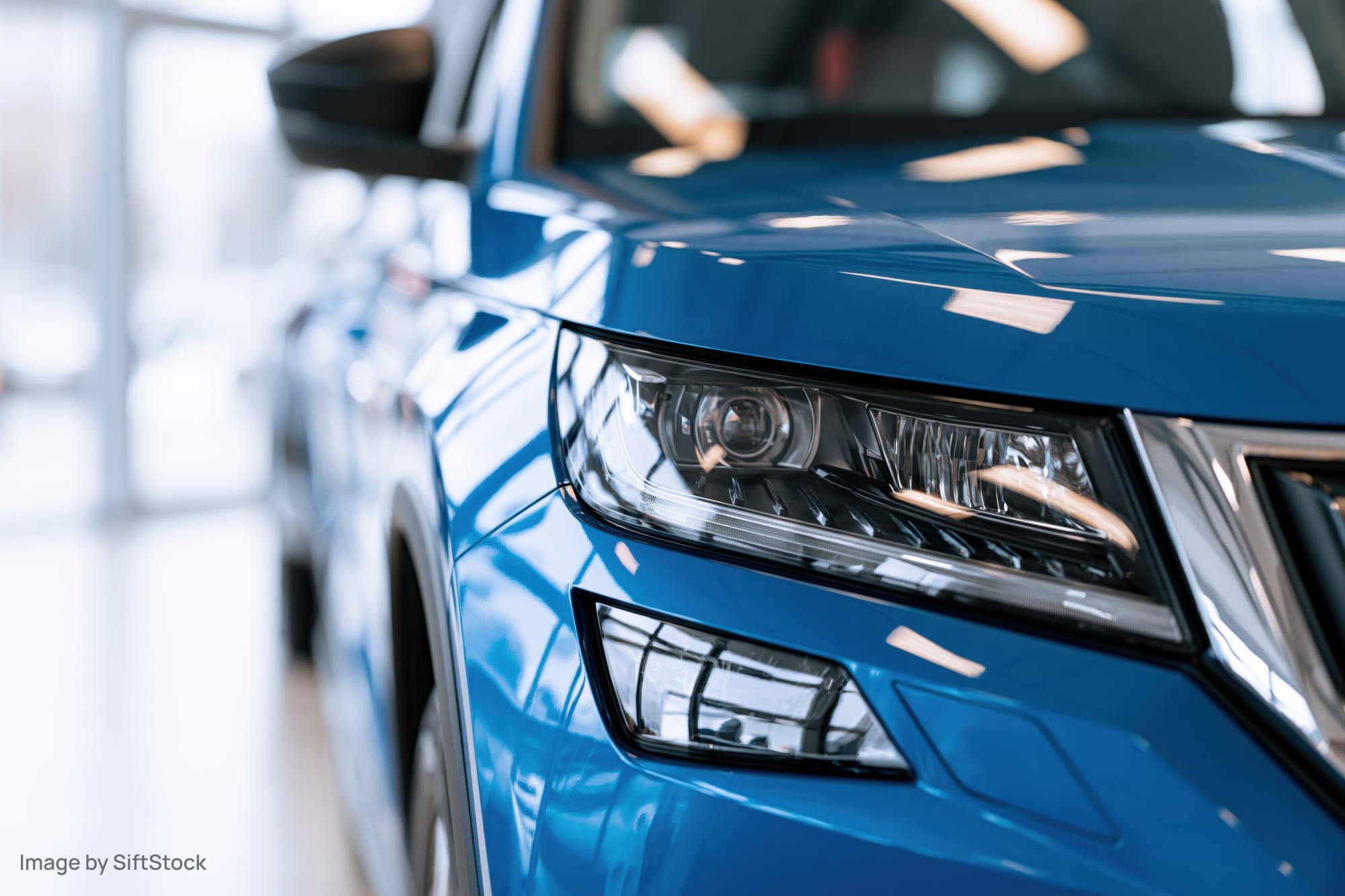 Close-up of blue suv front headlight and hood corner in showroom