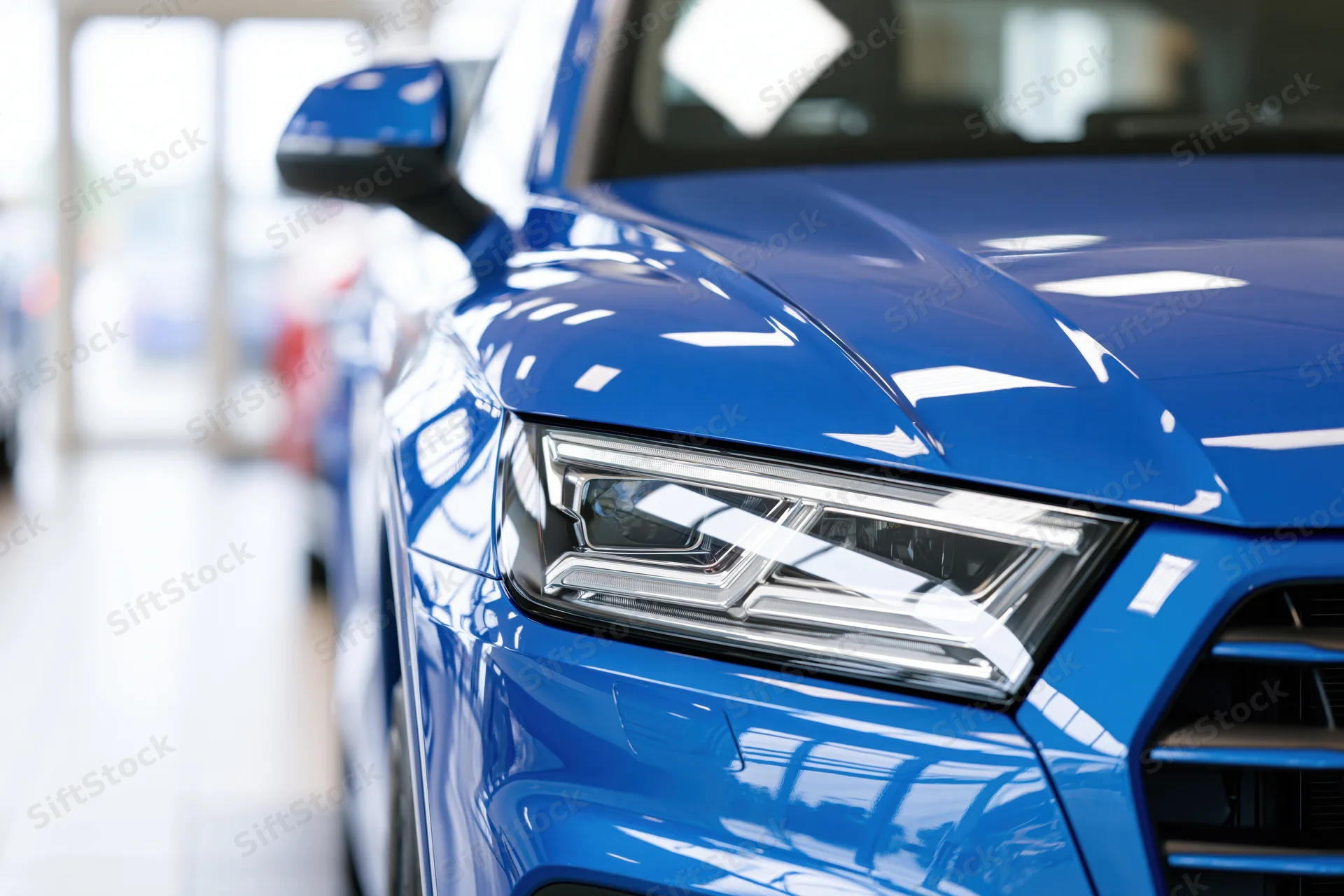 Close-up of blue suv front headlight and hood corner in showroom