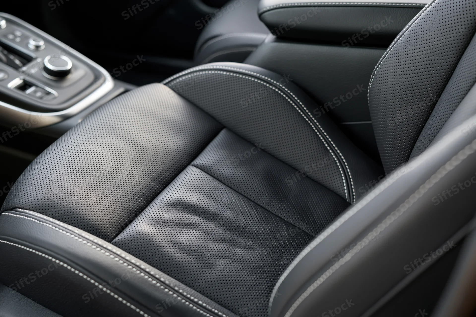 Close-up of black perforated leather driver's seat with white stitching in modern car interior
