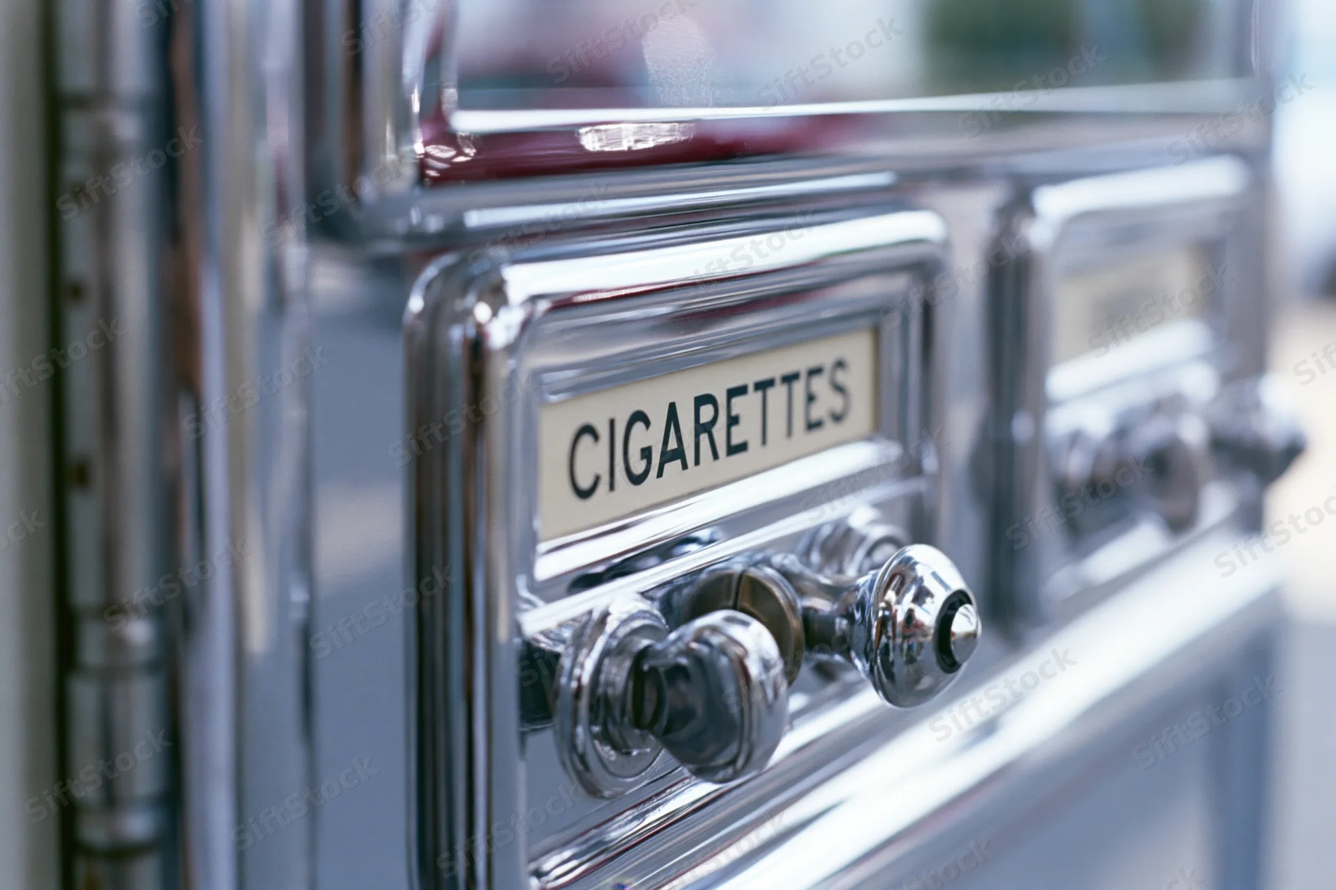 Close-up of vintage chrome cigarette vending machine with lever and label showing cigarettes