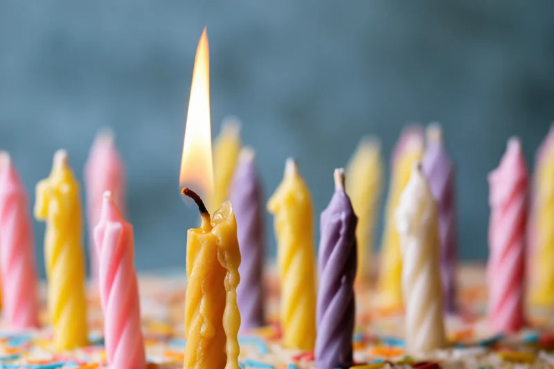 Close-up of colorful twisted birthday candles on a cake with one lit flame
