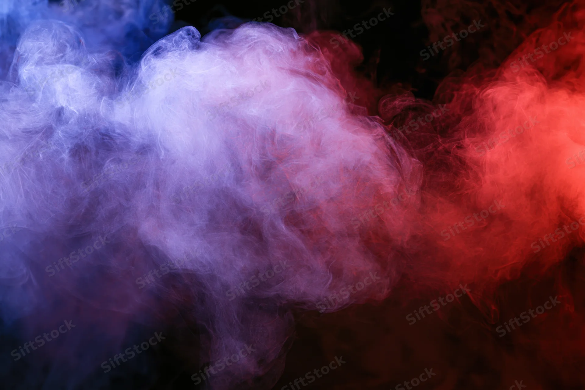 Swirling red and blue smoke drifting against a black background
