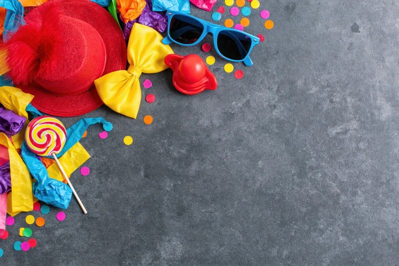Colorful carnival party props arranged in upper left corner on gray surface