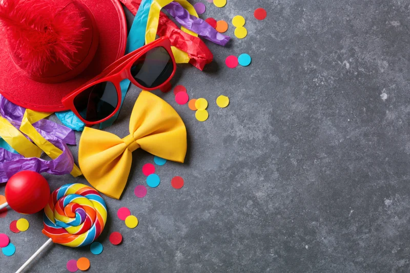 Colorful carnival party props arranged in upper left corner on gray surface with copyspace