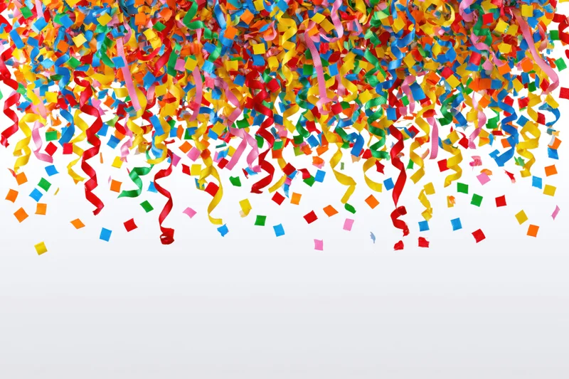 Colorful paper confetti and curled ribbon streamers falling against white background