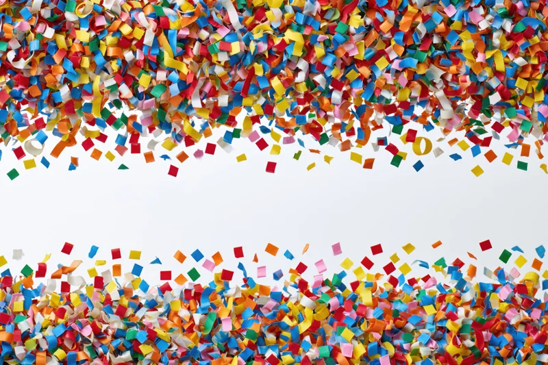 Colorful paper confetti and curled ribbon streamers falling in a frame with copyspace