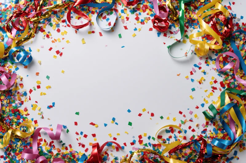 Colorful confetti and curled ribbon streamers scattered around a white center copyspace for celebration decoration