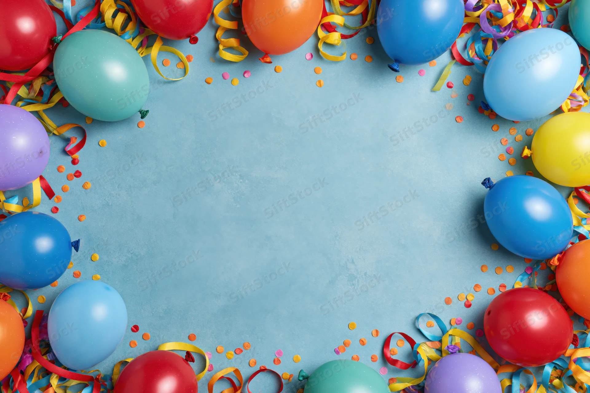 Colorful party balloons and curled ribbon streamers arranged in a frame around a blue surface with confetti and copyspace