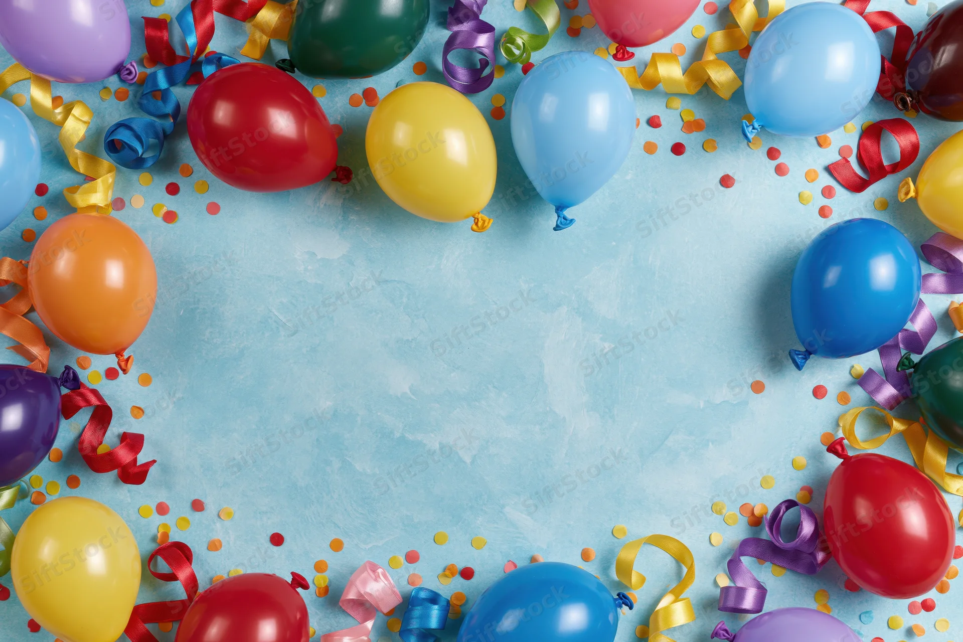 Colorful party balloons and curled ribbon streamers arranged in a border around a light blue textured surface with confetti, leaving central copyspace