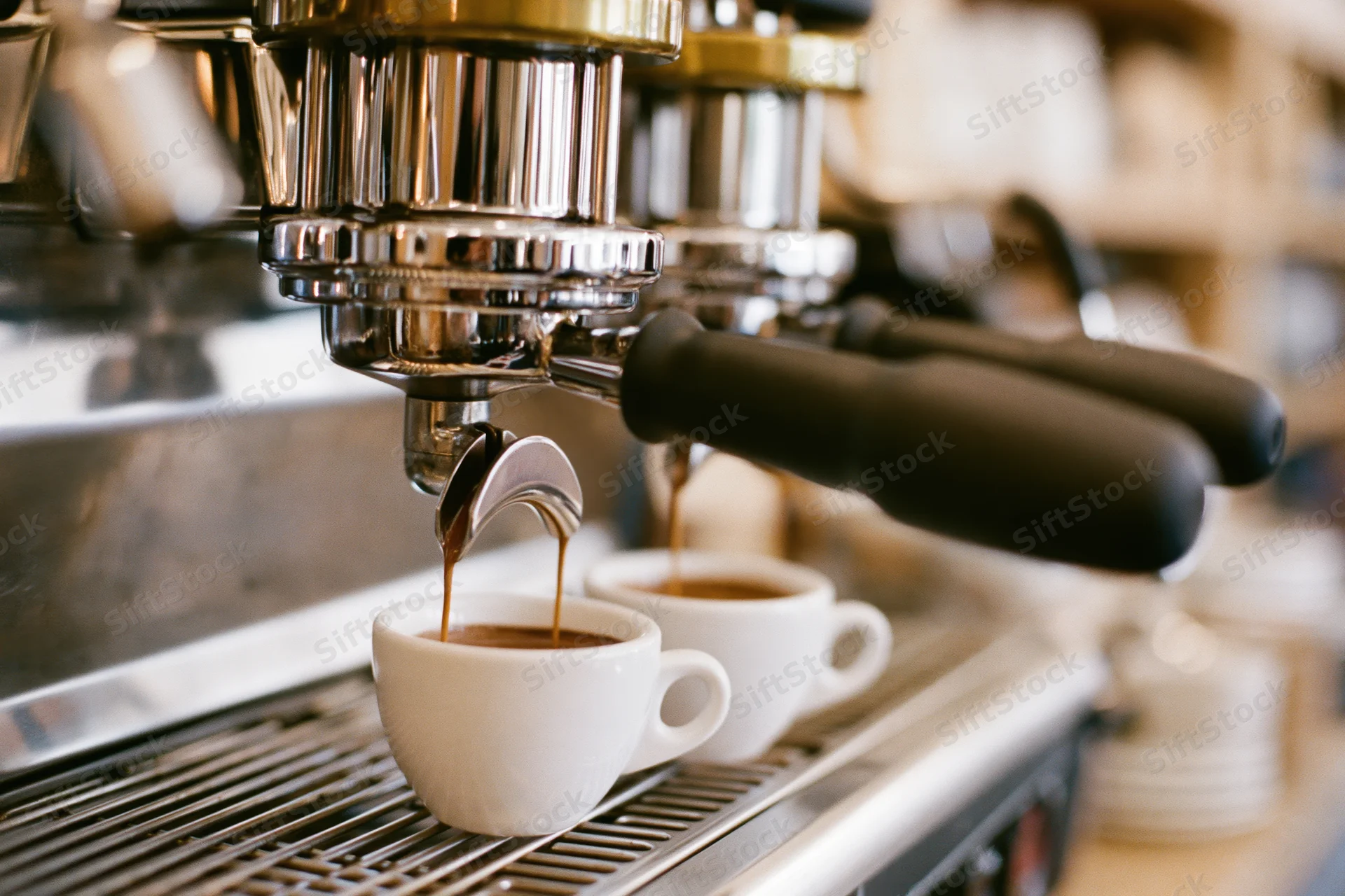 Espresso machine brewing coffee into white cups on a commercial countertop