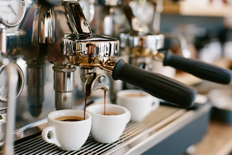 Espresso machine brewing coffee into white cups on a cafe counter