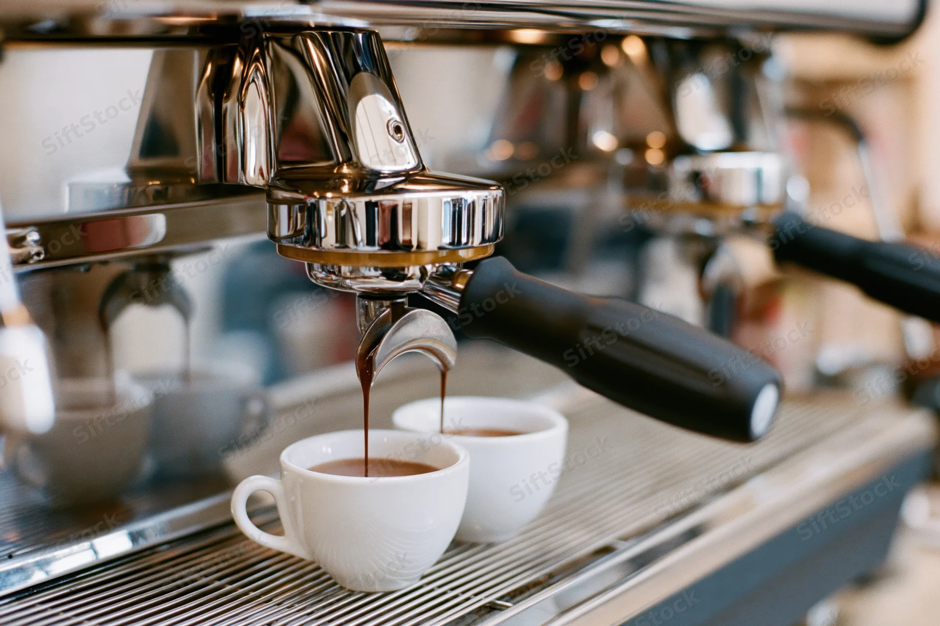 Espresso machine brewing coffee into two white cups on a metal counter