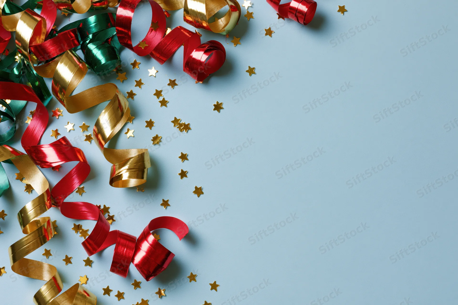 Curled metallic streamers and star-shaped confetti scattered on a blue surface with copyspace