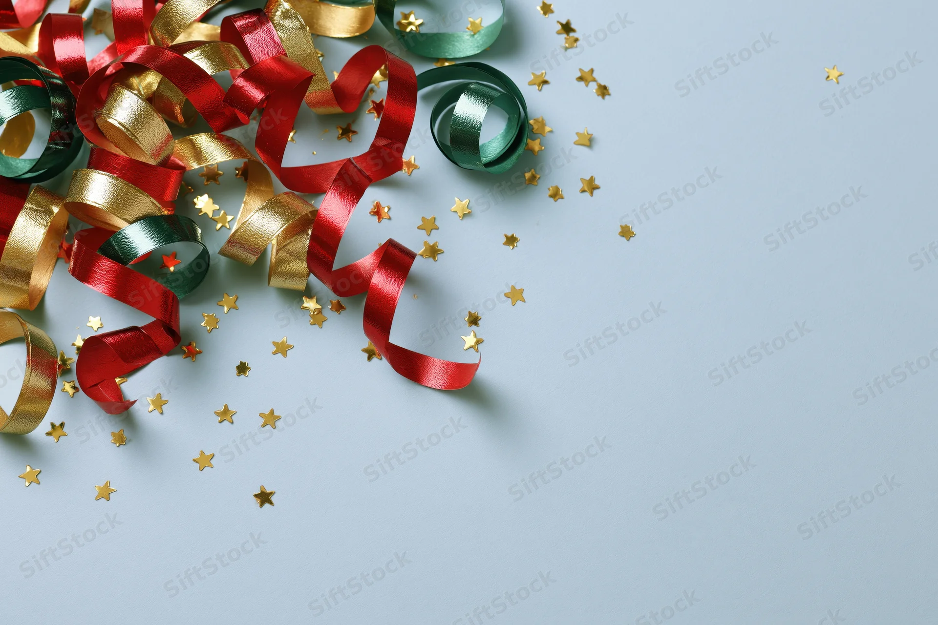 Curled metallic streamers and star-shaped confetti scattered on a light blue surface with copyspace