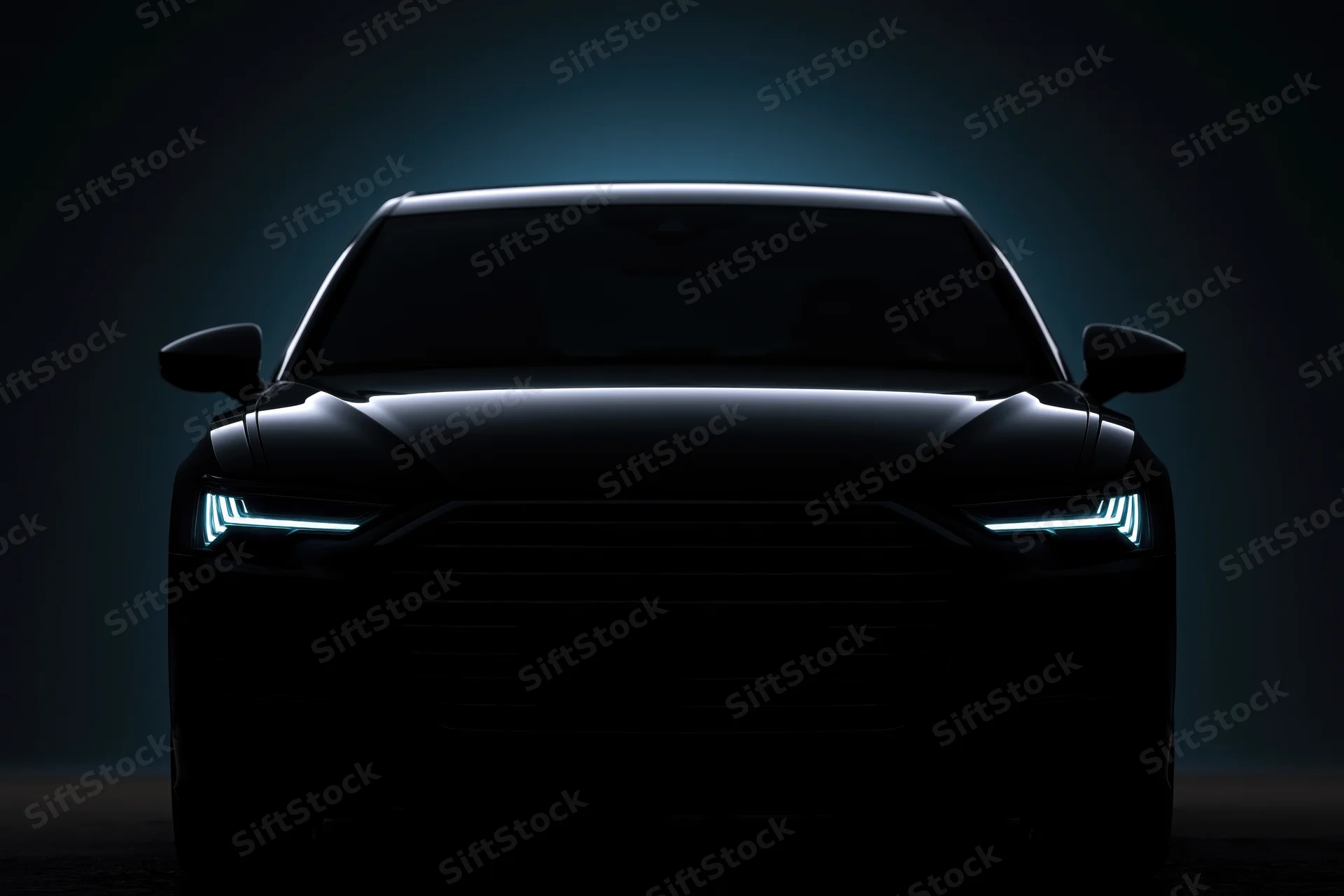 Dark sedan silhouetted head-on with glowing led headlights in a studio setting