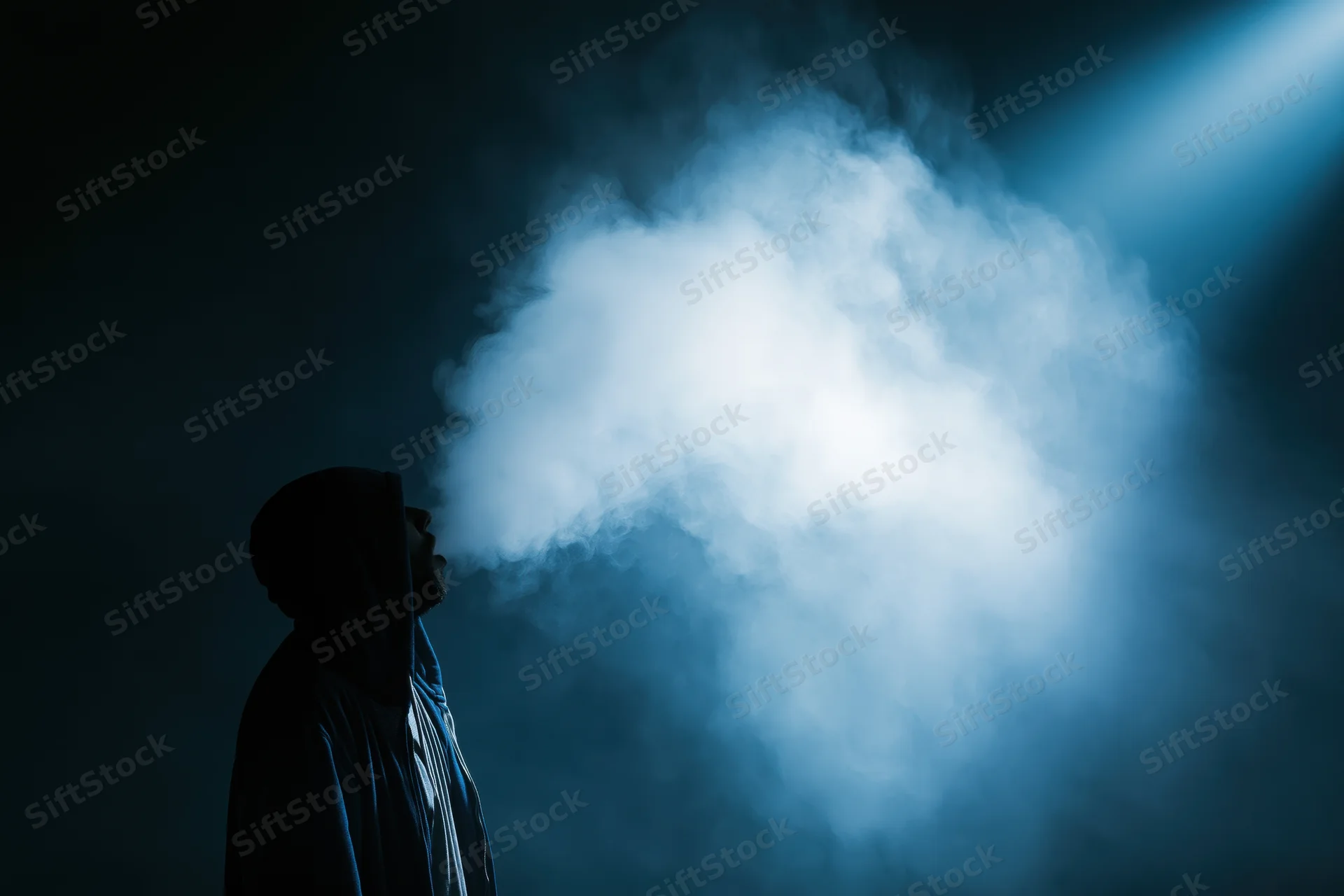 Hooded figure exhaling a large cloud of vapor in a dark blue-lit space