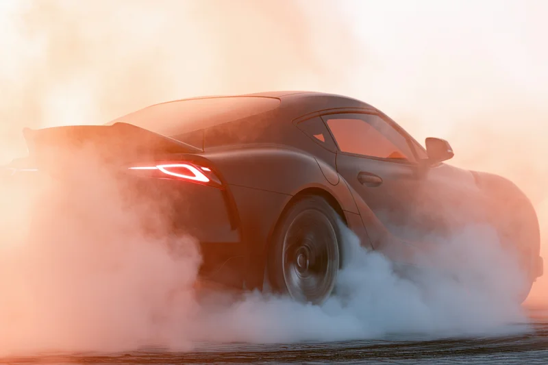 Dark sports car performing burnout on race track with smoke and glowing tail lights