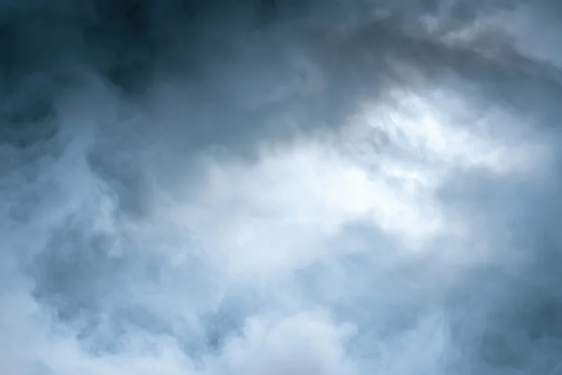 Dense billowing smoke filling the frame with swirling gray and white clouds against a dark blue sky