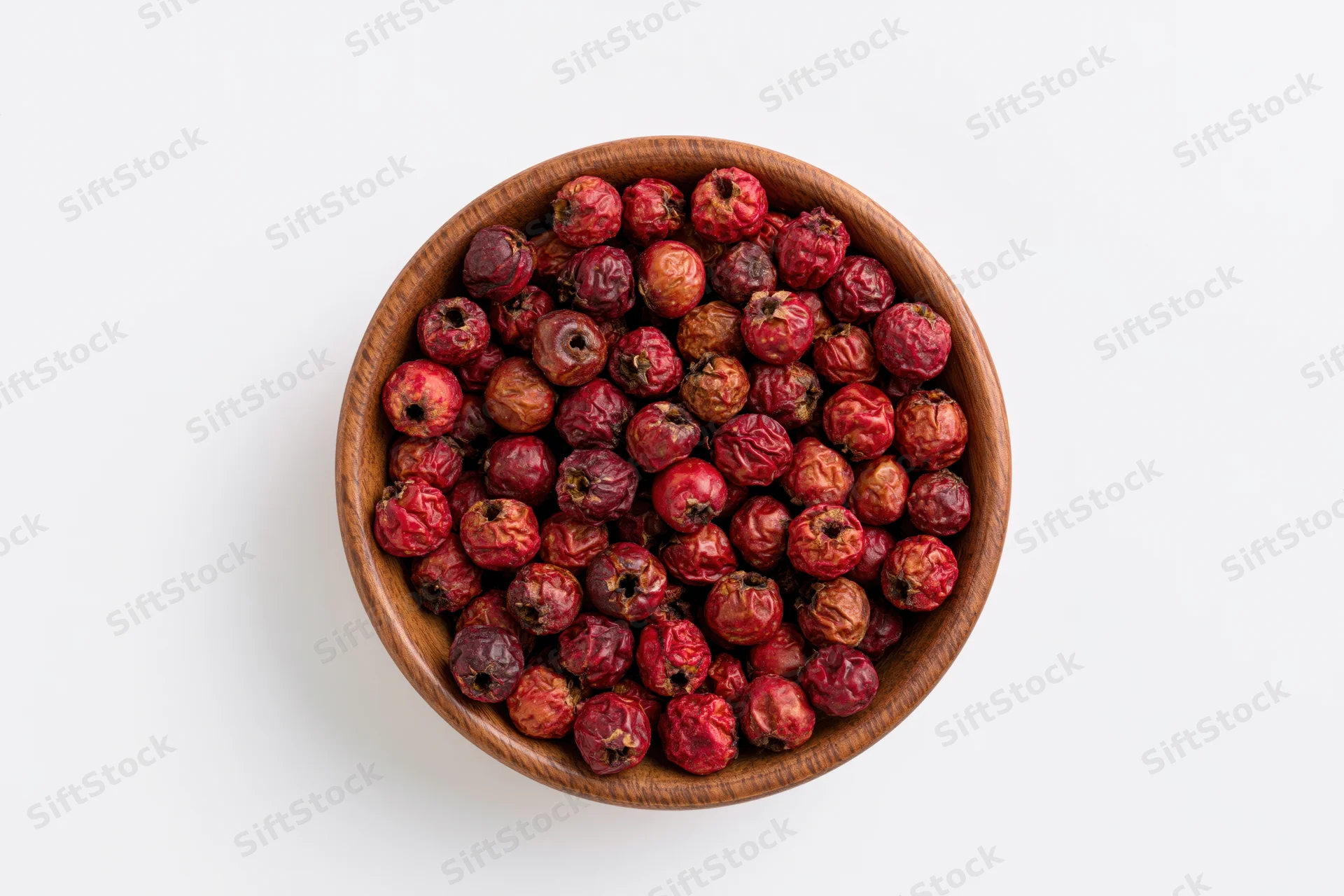 Dried red hawthorn berries in a wooden bowl on white background