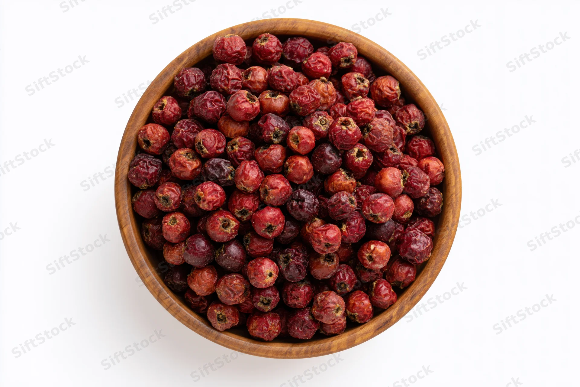 Dried red hawthorn berries in a small round wooden bowl on white background