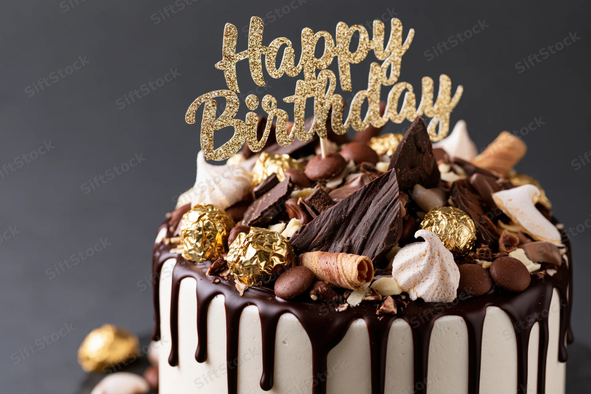 Chocolate drip birthday cake topped with gold glitter topper and assorted candies