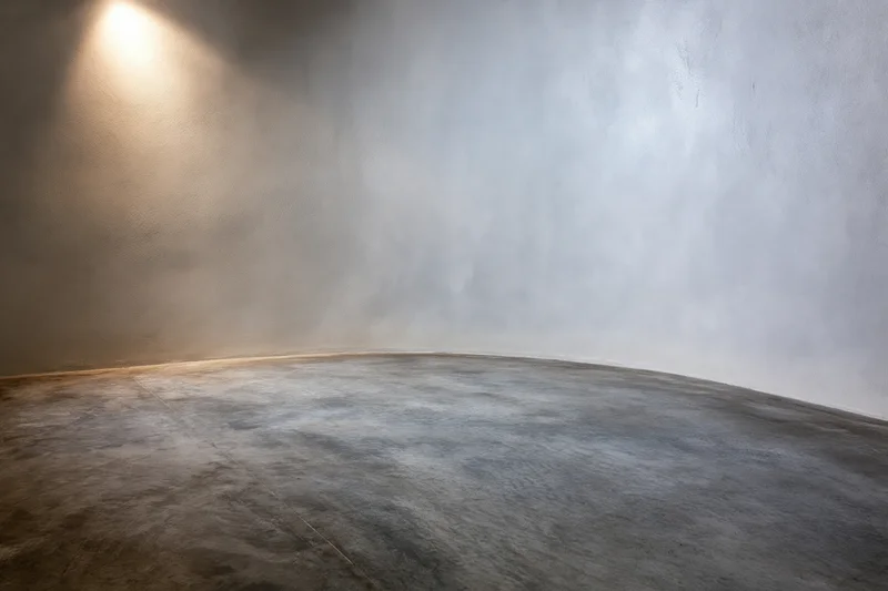 Empty studio space with concrete floor and grey wall under spotlight
