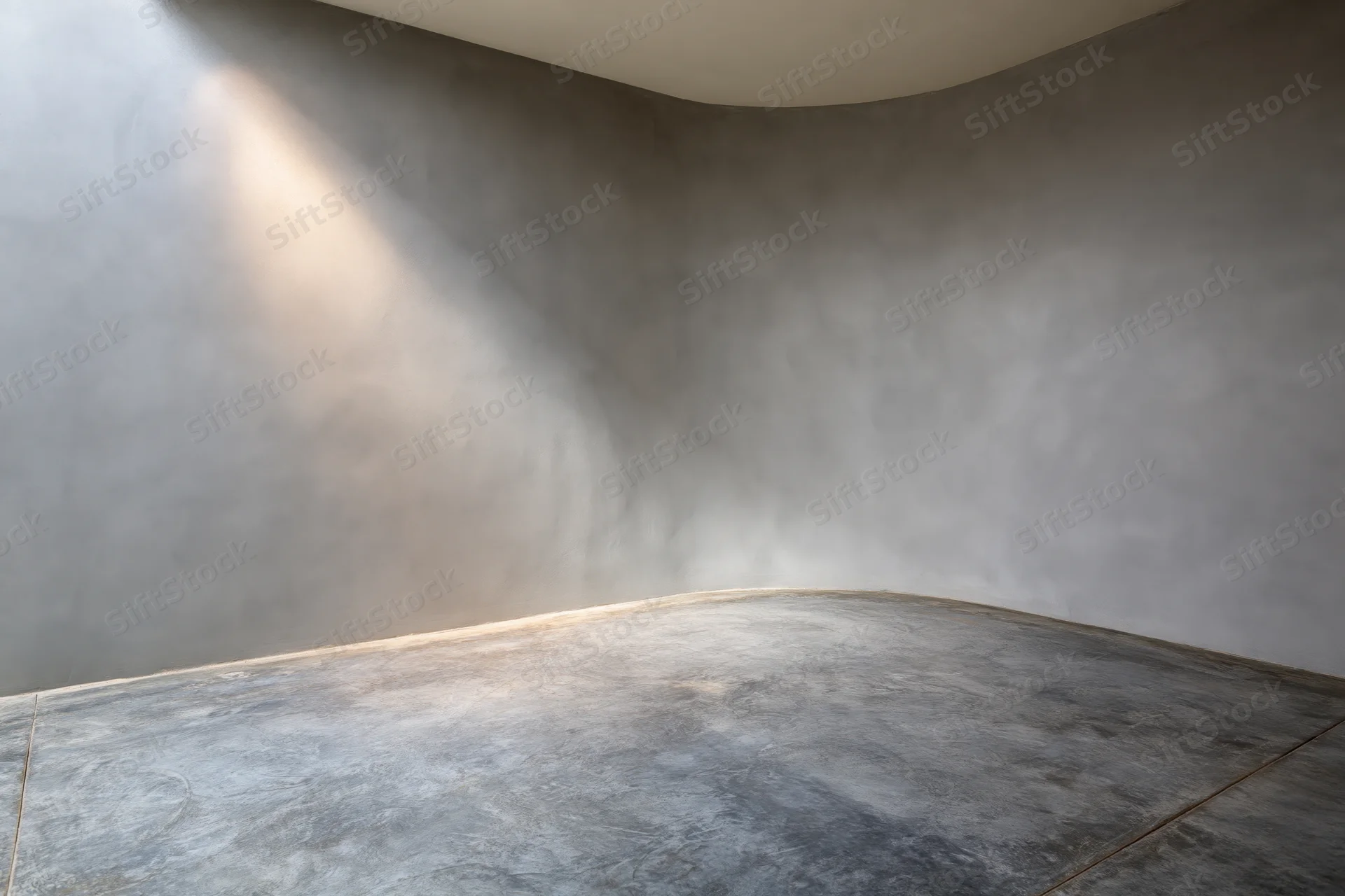 Empty studio interior with curved concrete walls and floor, lit by natural light from above