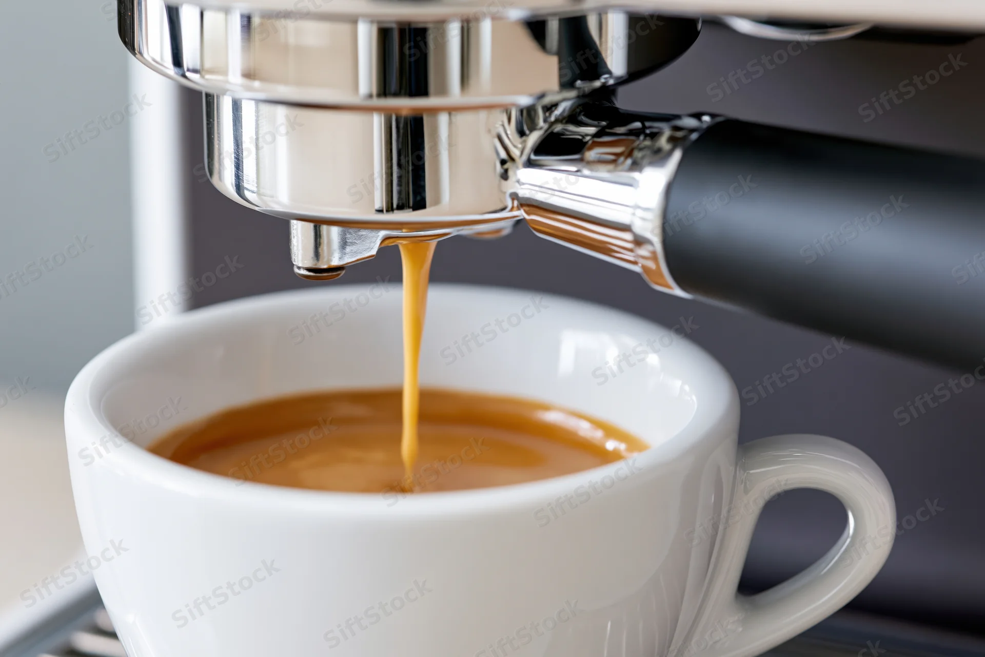 Espresso machine pouring coffee into a white ceramic cup on a kitchen countertop