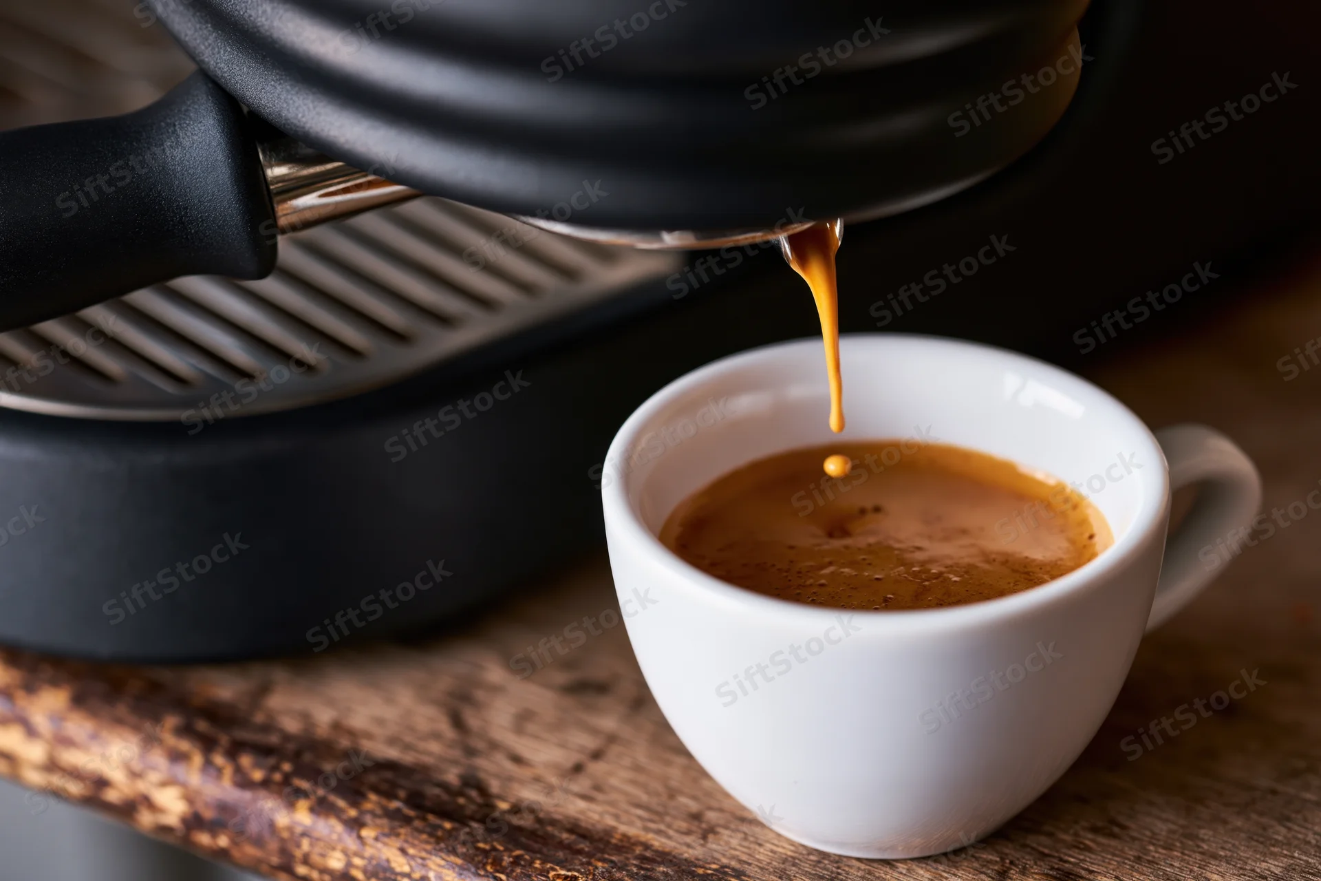 Espresso streaming from a portafilter into a white ceramic cup on a wooden table