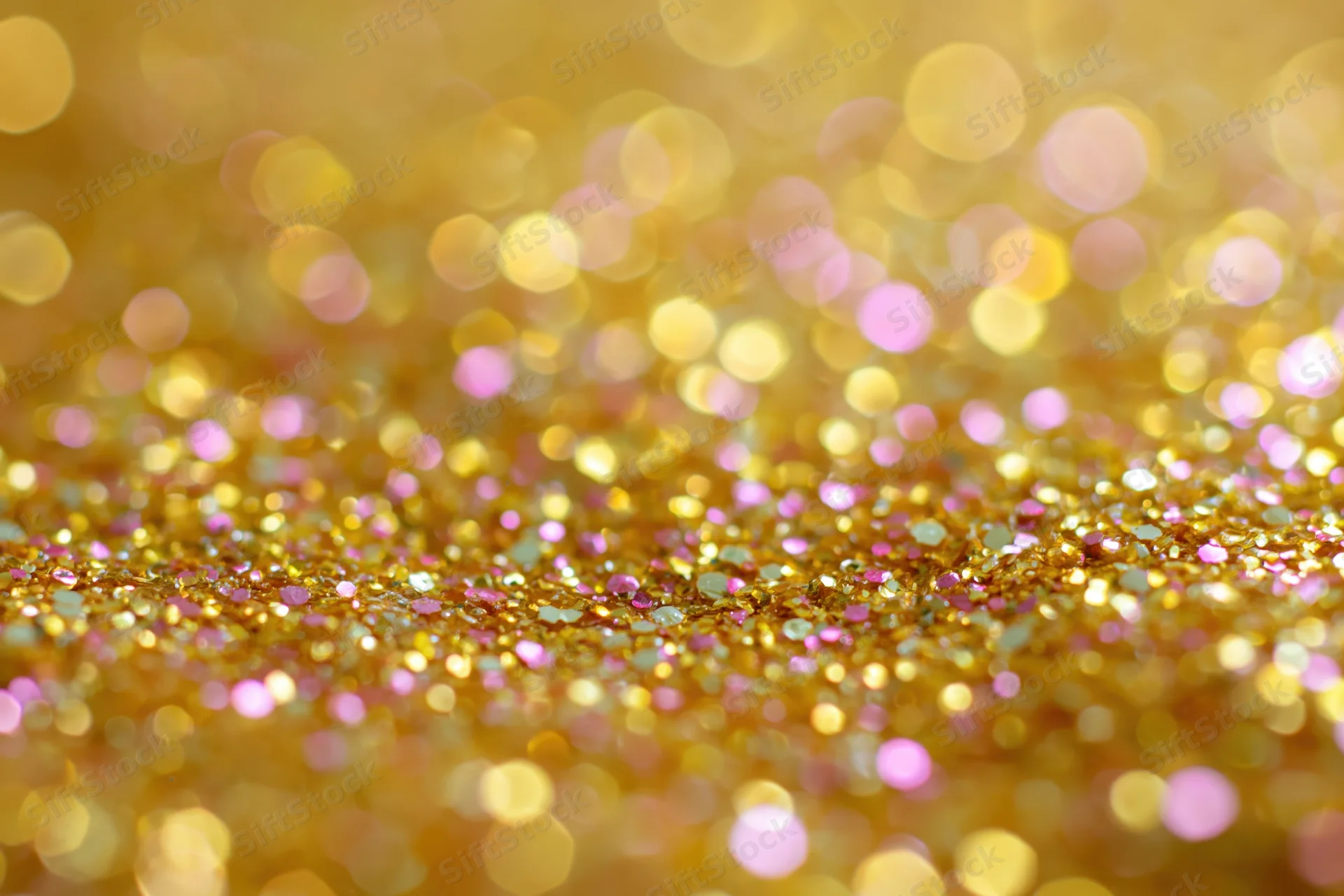 Close-up of gold and pink glitter surface with bokeh effect
