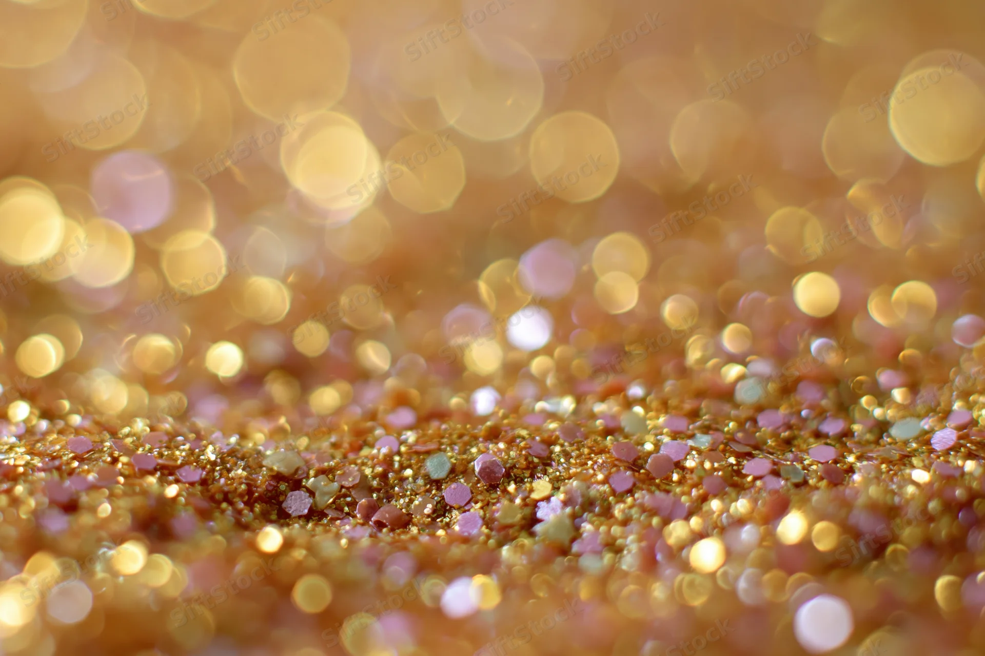 Close-up of gold and pink glitter surface with bokeh background