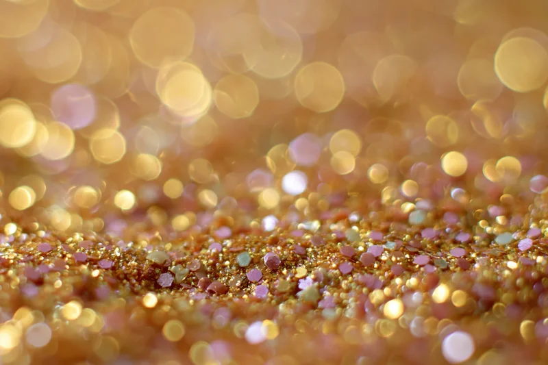 Close-up of gold and pink glitter surface with bokeh background