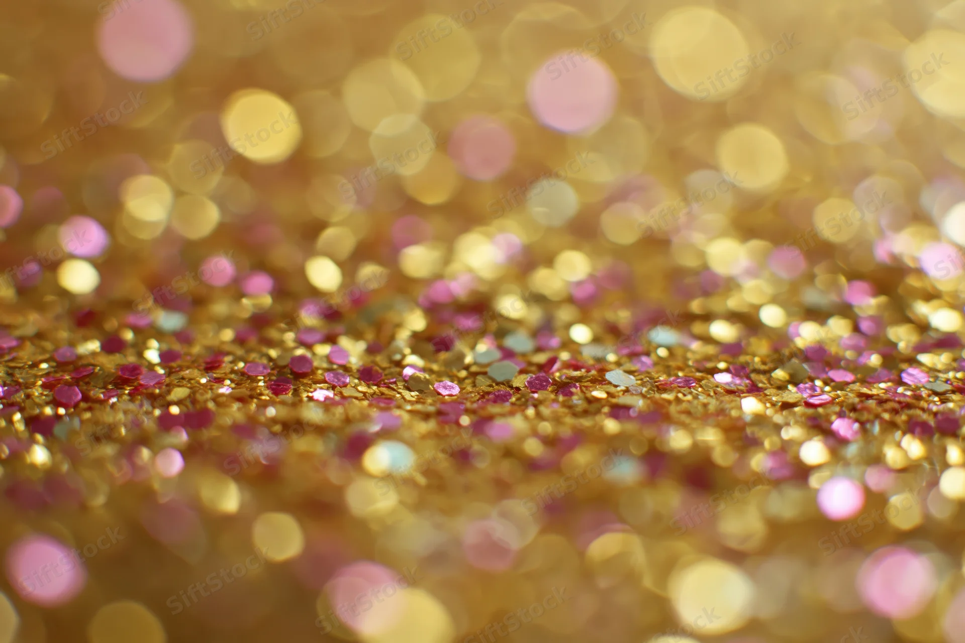 Close-up of gold and pink glitter surface with bokeh effect
