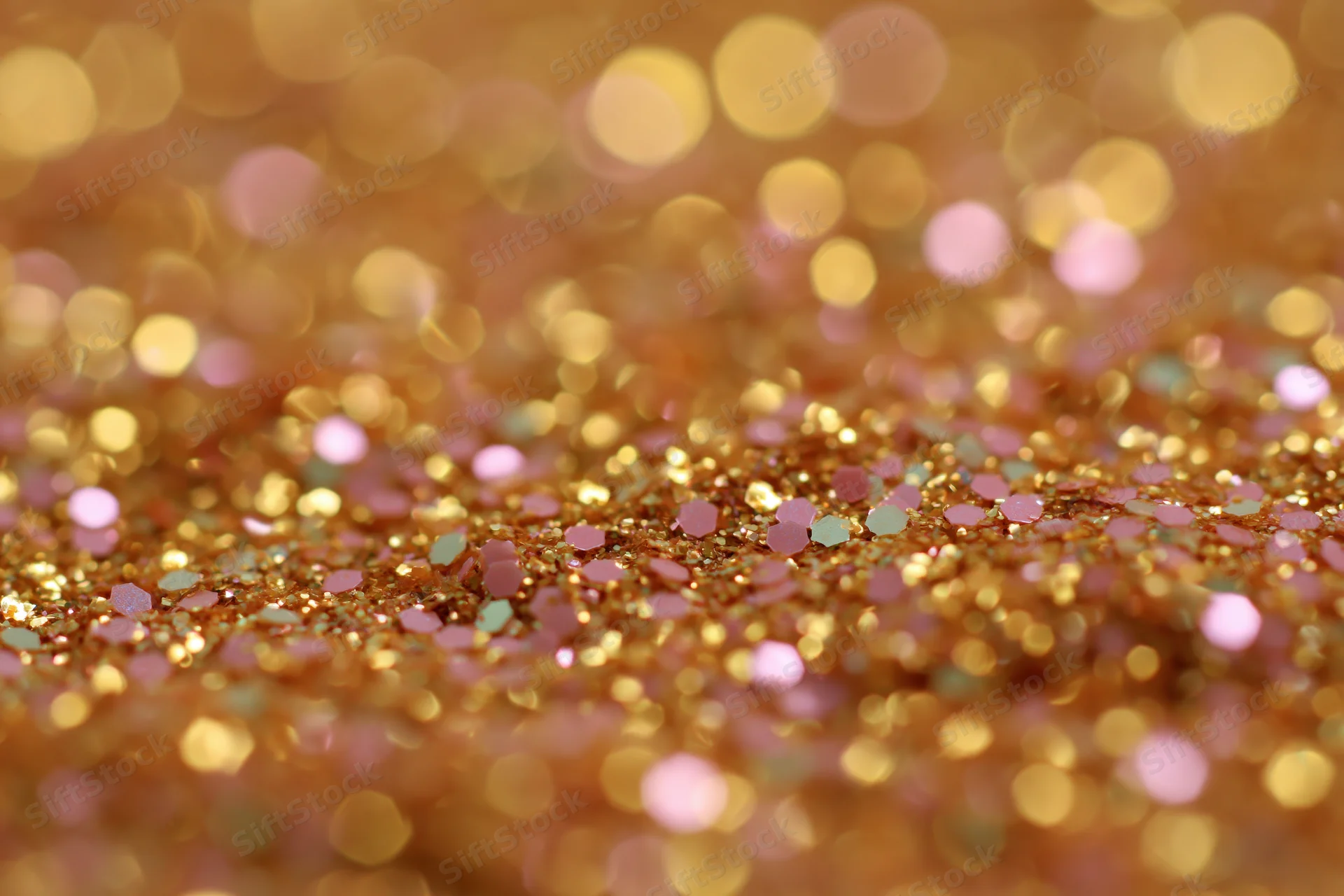 Close-up of gold and pink glitter surface with bokeh effect