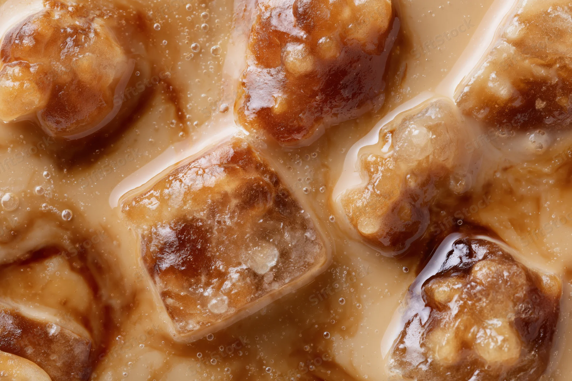 Closeup of iced coffee surface with floating ice cubes and creamy froth