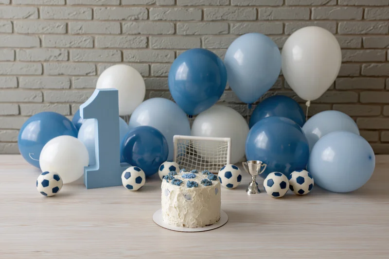 First birthday party setup with soccer theme cake, balloons, number one, trophy and goal on table