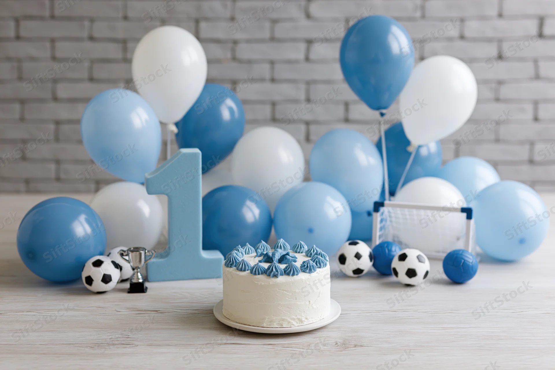 First birthday party setup with cake, balloons, soccer toys and number one decoration on wooden table