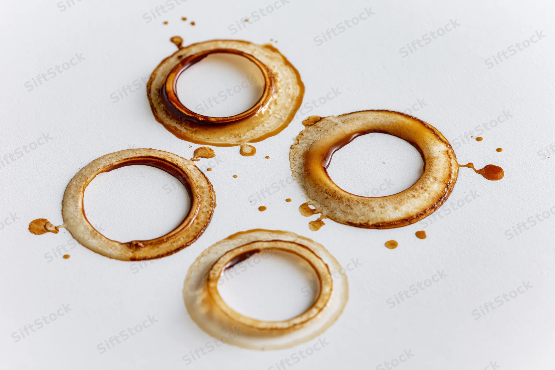 Coffee cup ring stains of varying sizes scattered across a white surface
