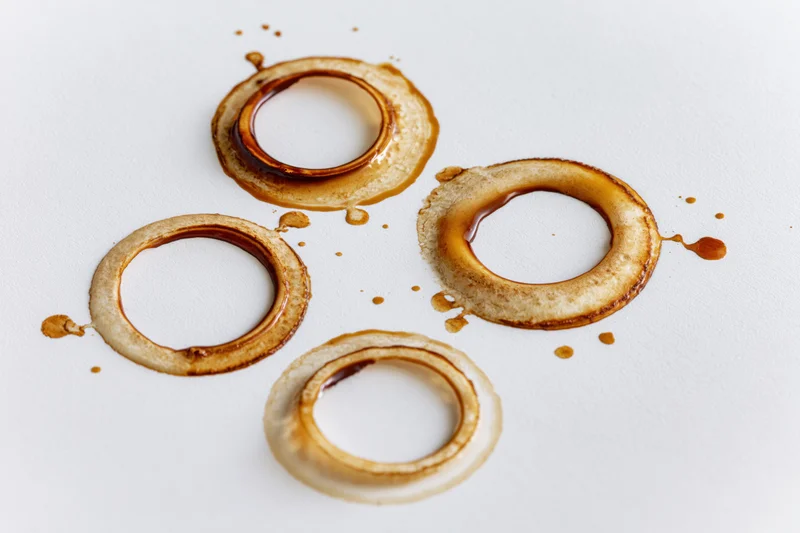 Coffee cup ring stains of varying sizes scattered across a white surface
