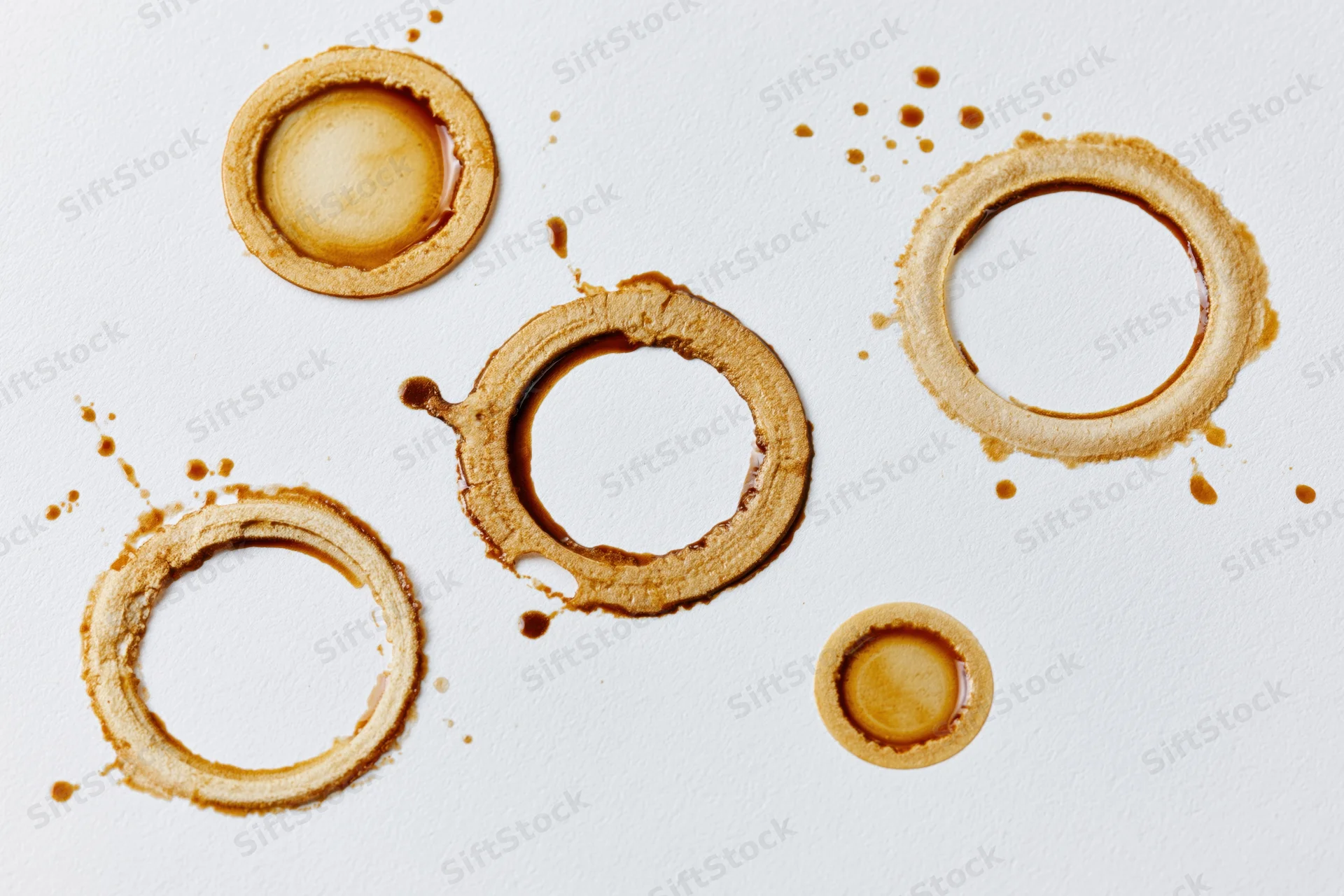 Coffee cup ring stains of varying sizes scattered across a white surface