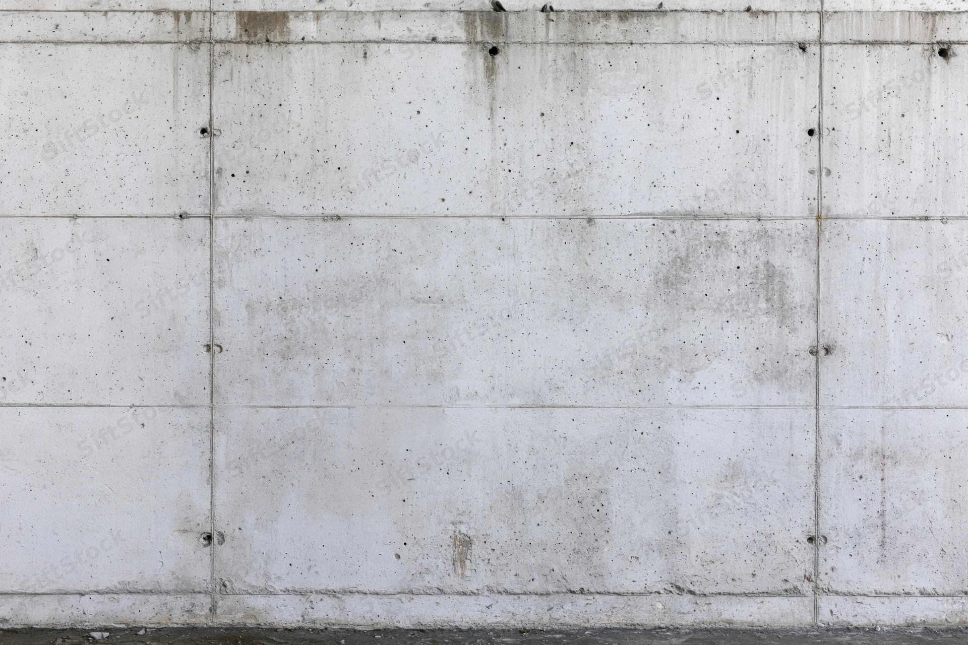 Flat concrete wall with grid joints and weathered texture filling the frame