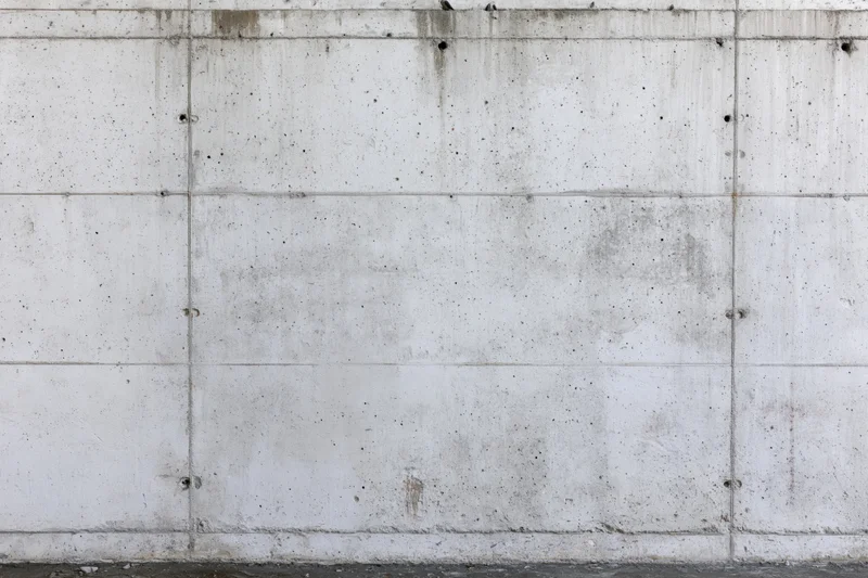 Flat concrete wall with grid joints and weathered texture filling the frame