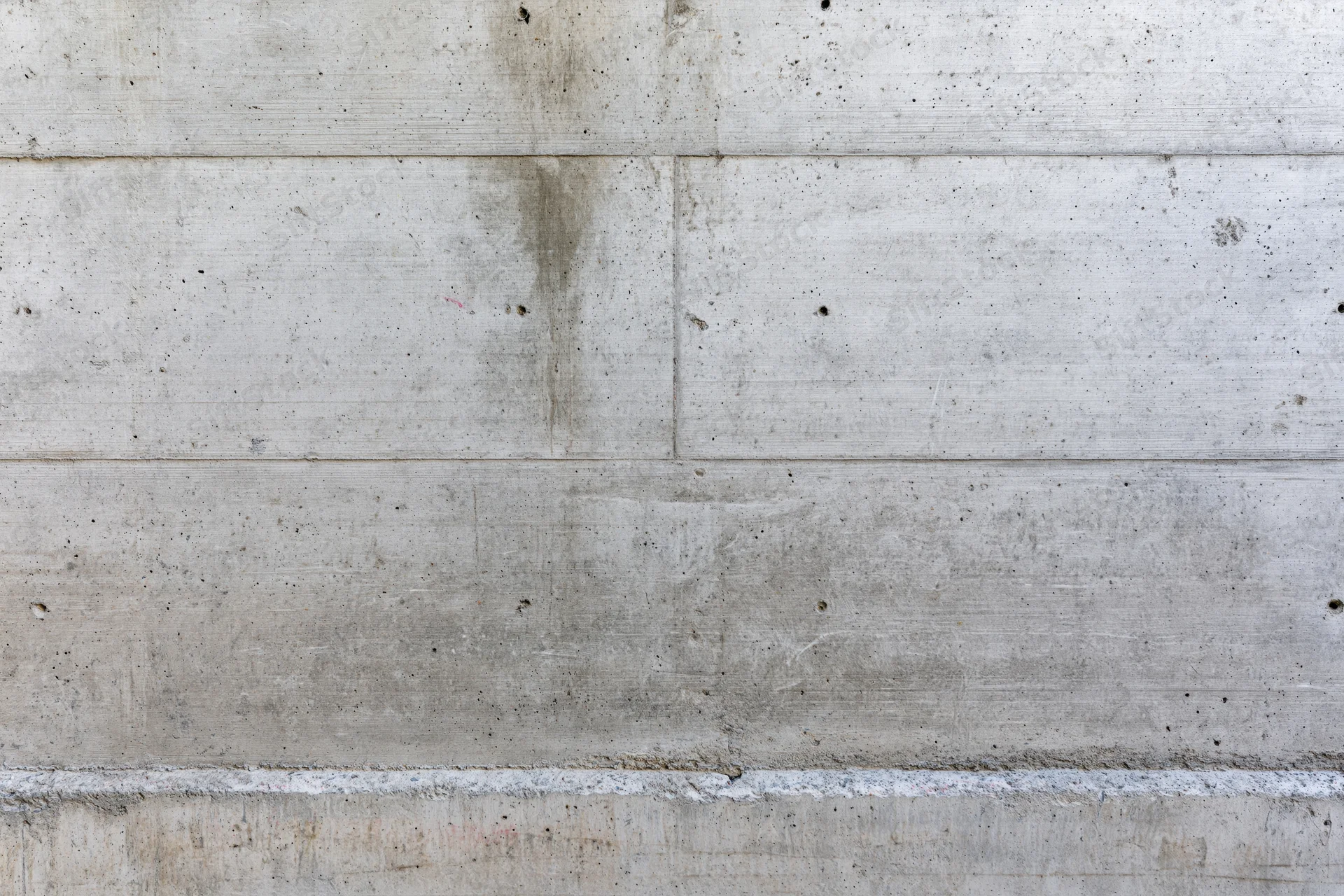 Flat bare concrete wall filling the frame with horizontal seams and textured surface