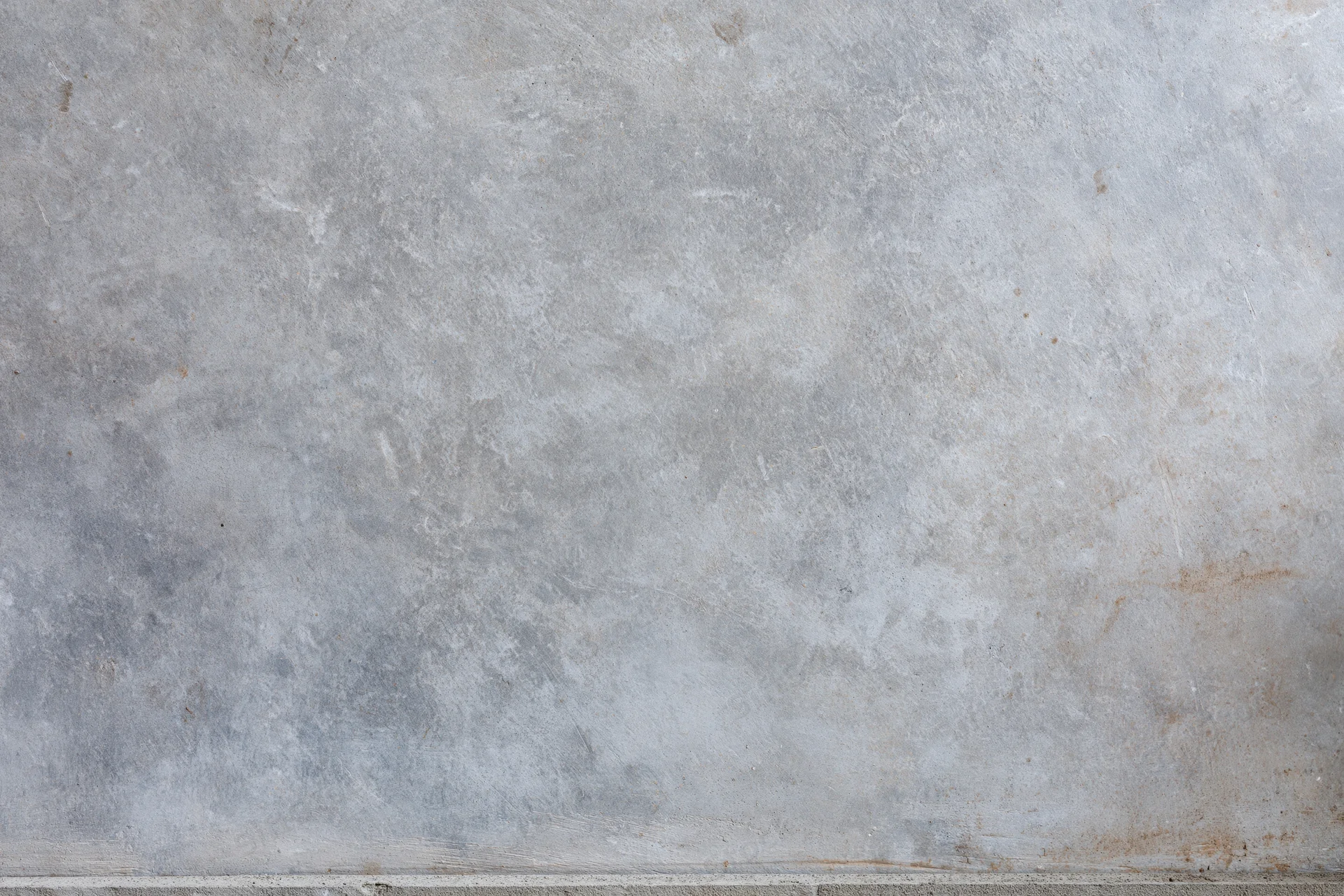 Flat concrete wall surface filling the frame with visible texture and minor stains
