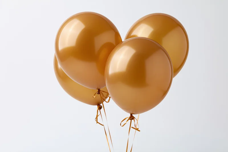 Four glossy gold helium balloons tied together in a cluster against a white background