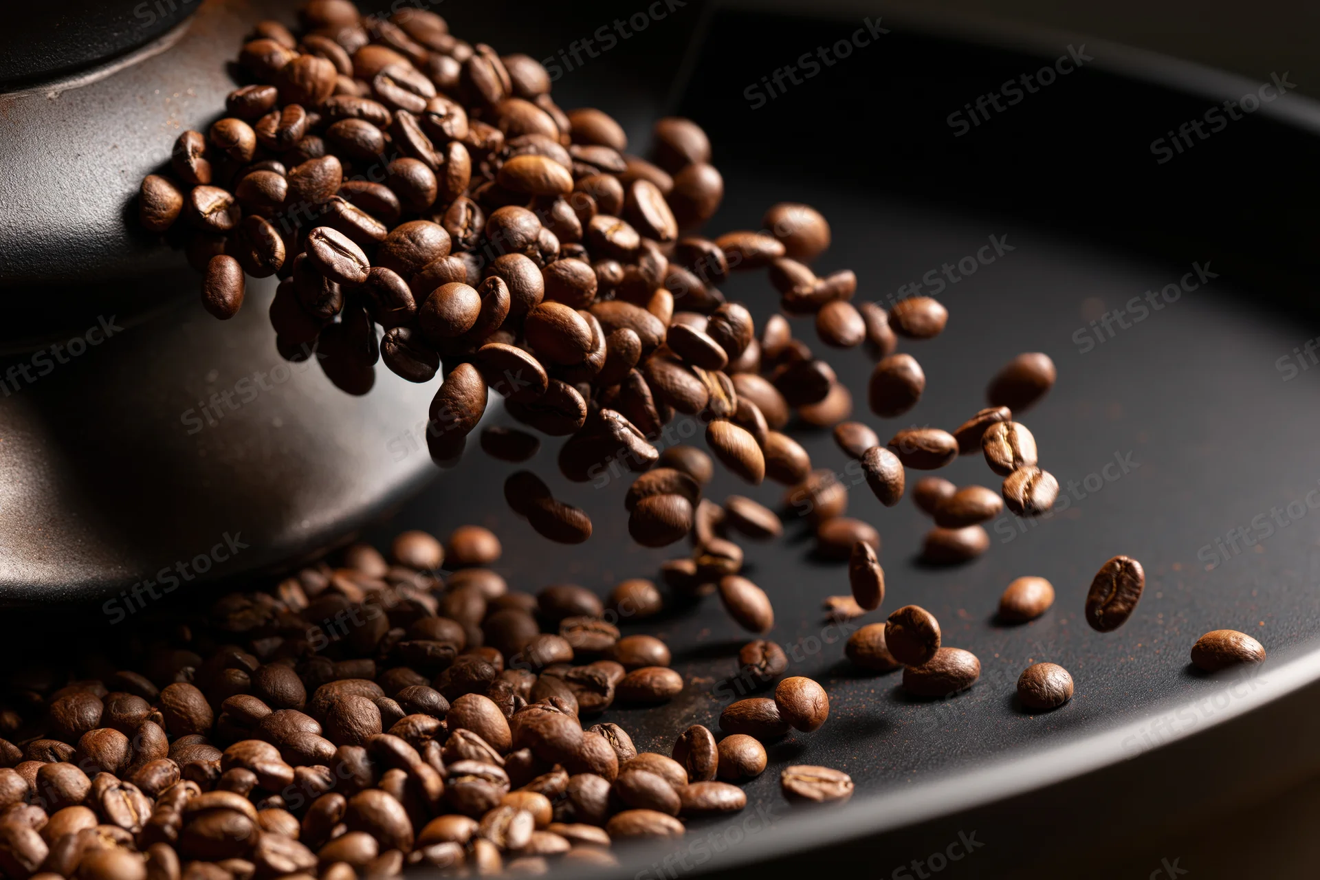 Roasted coffee beans cascading from a matte ceramic container onto a dark surface