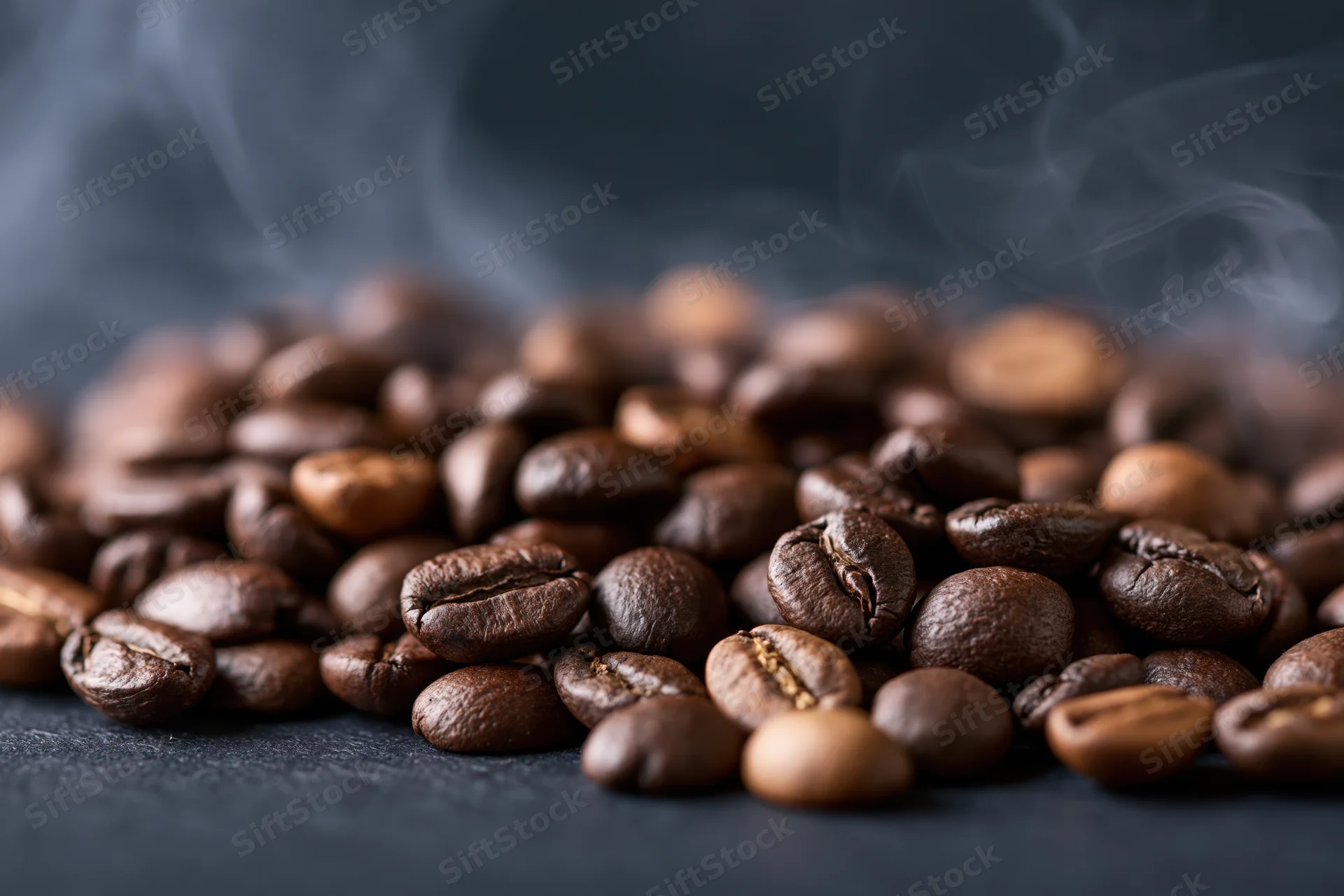 Freshly roasted coffee beans with rising steam on a dark surface