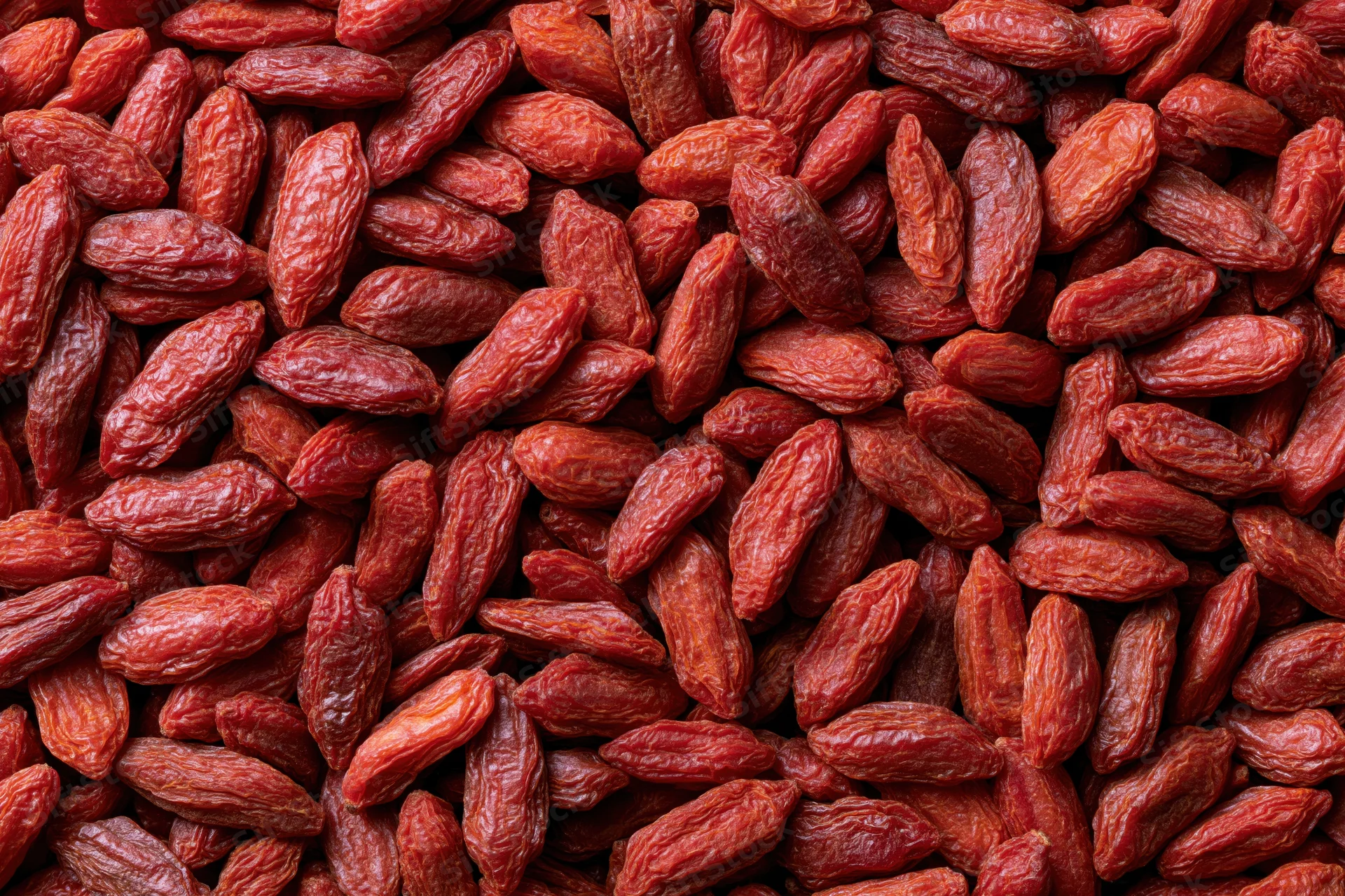 Dried goji berries filling the frame as a textured background with copyspace on the sides